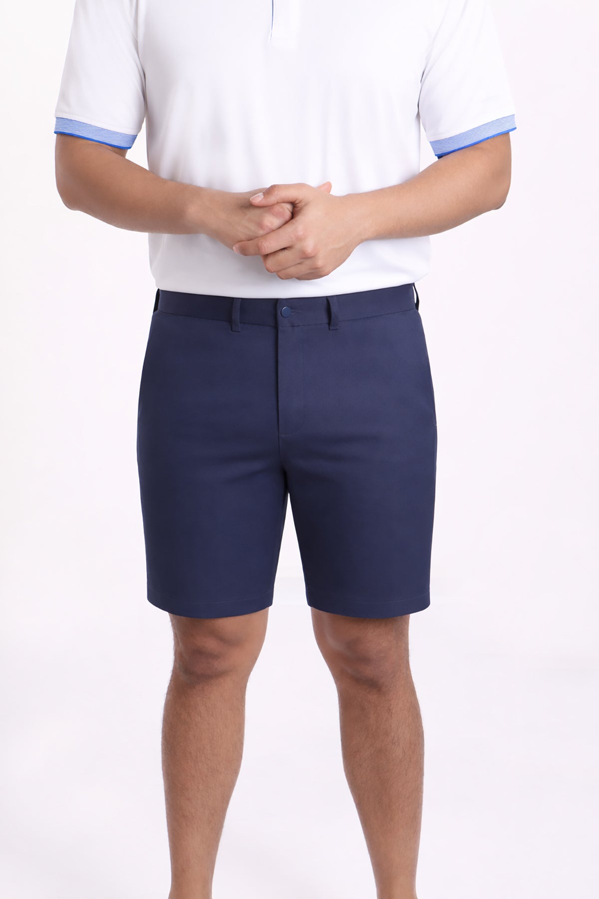 Person wearing navy shorts and a white polo shirt with blue trim on a white background